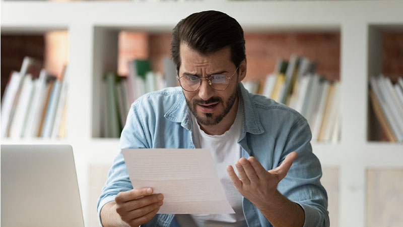 Homem a olhar para fatura de serviços com ar confuso